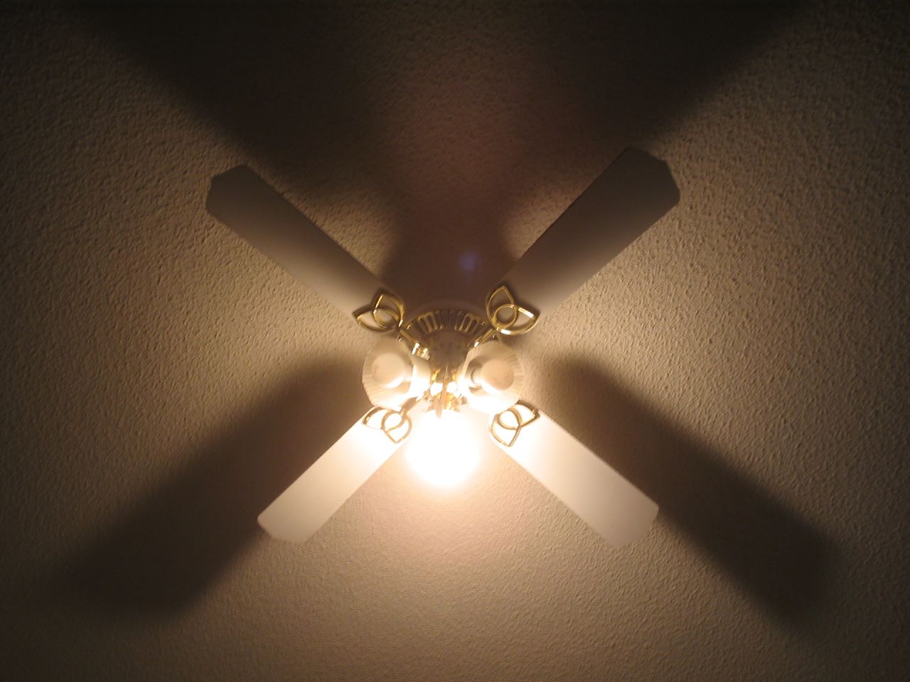 a ceiling fan is shining on the wall