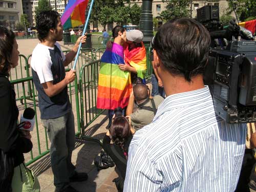 a man is talking to the media and holding a rainbow flag