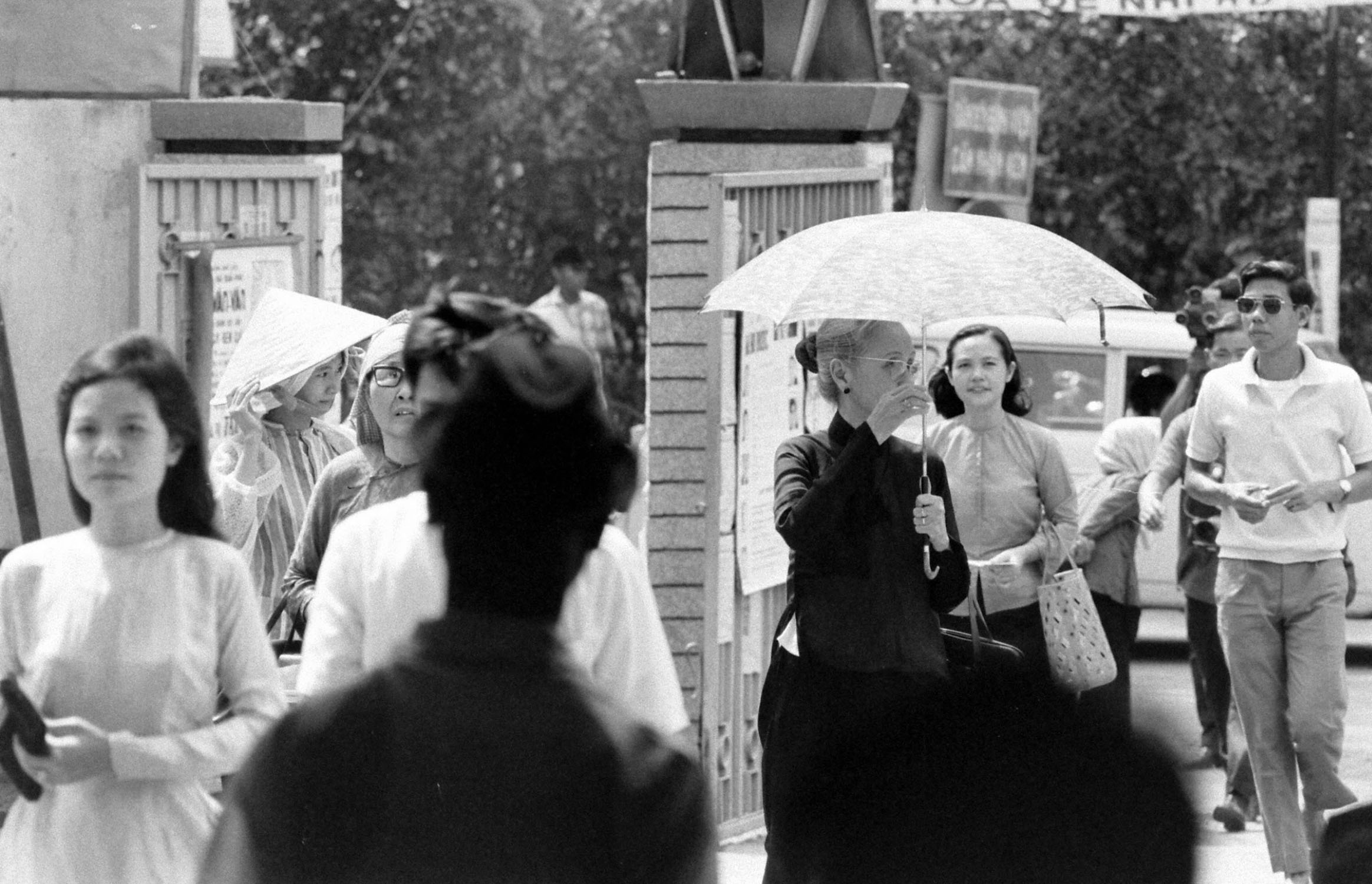 a black and white image of people standing with umbrellas in the rain