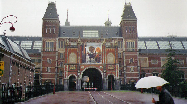 man with white umbrella walking near large building