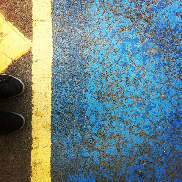 two yellow lines painted on the ground next to a pair of shoes
