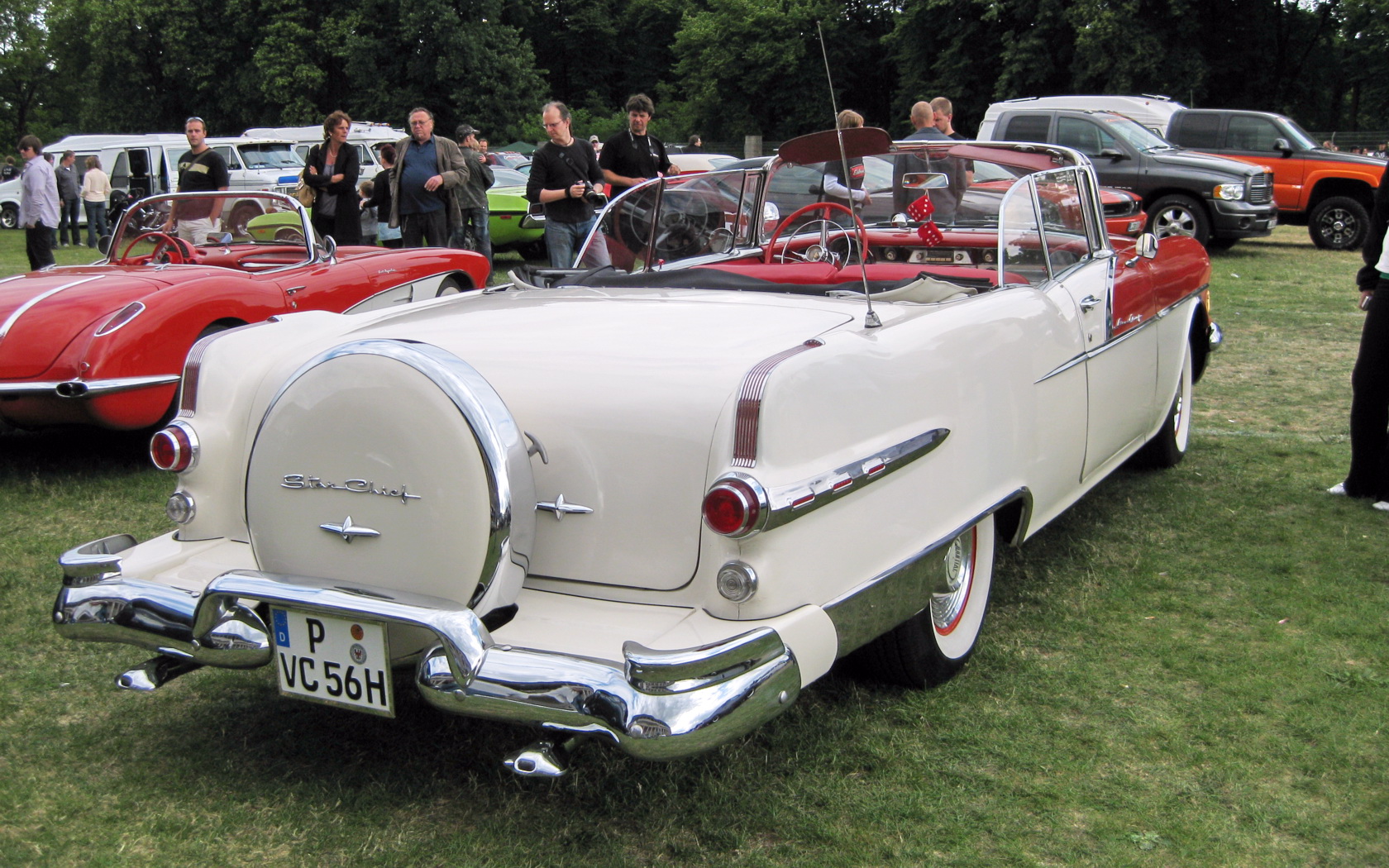vintage cars on display on grassy field next to trees
