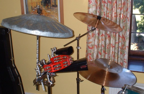 a drum kit sitting in front of a window next to a guitar