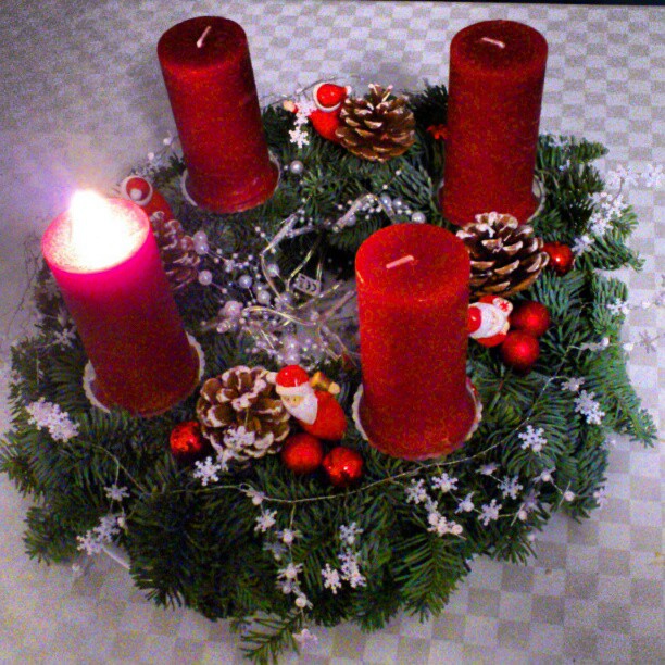 two red candles sit on top of a wreath