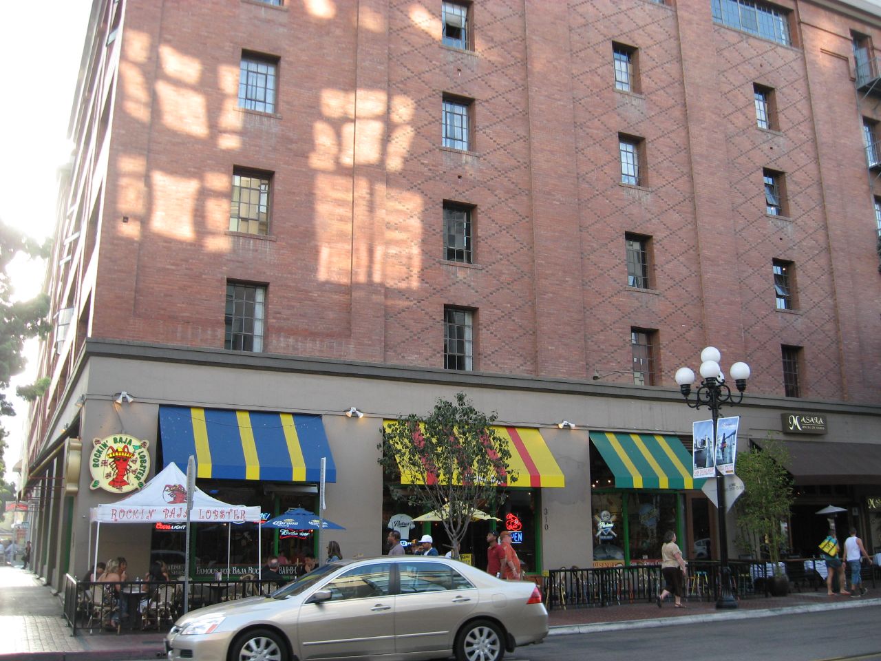 a car parked outside of an orange brick building with several awnings