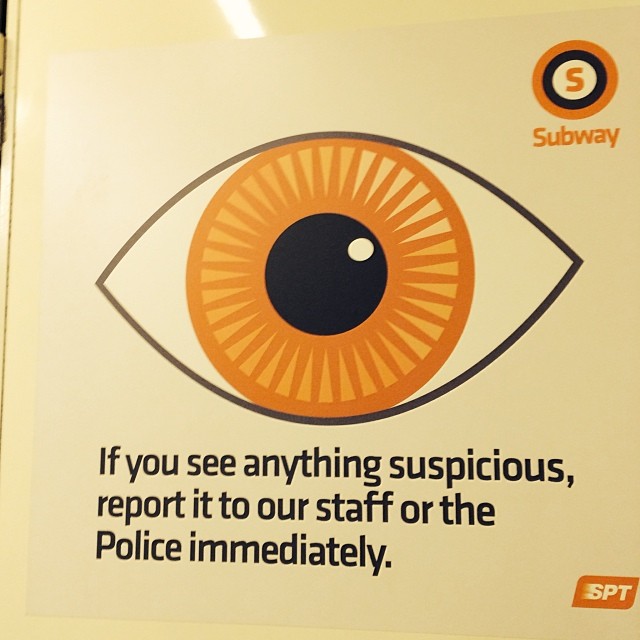 the sign is showing an eye, saying if you see anything suspicious, report it to our staff