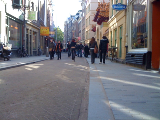 people walk down the sidewalk of an urban street