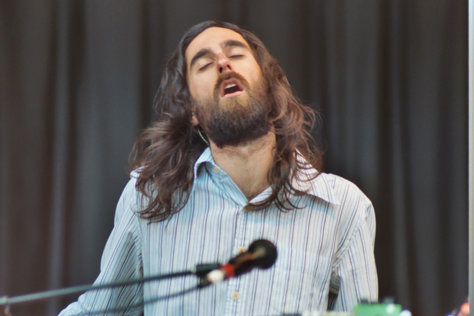 the bearded man has a microphone to sing and his eyes closed
