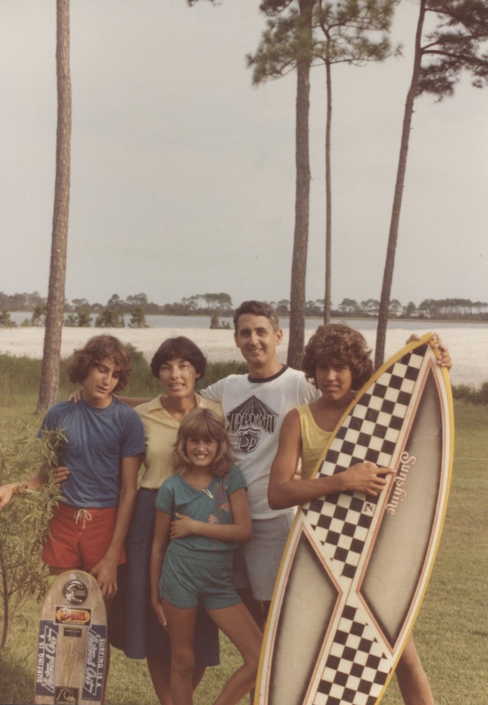 a family poses with their surf board in the grass