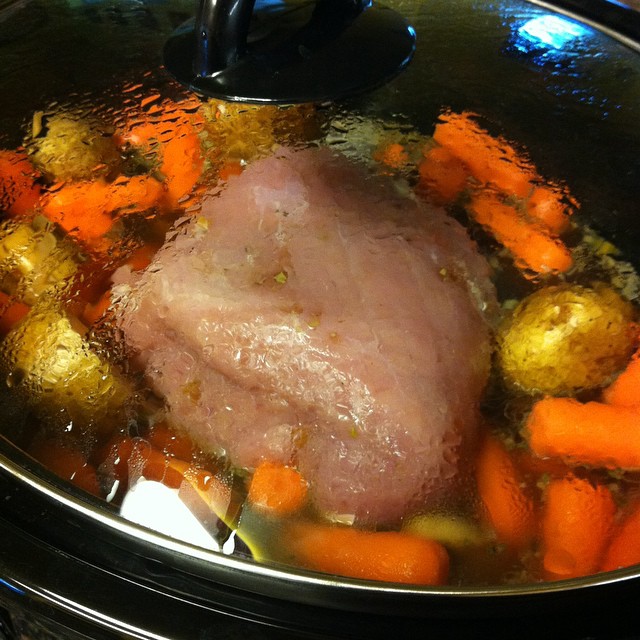 a large meat in a pan with broth and carrots