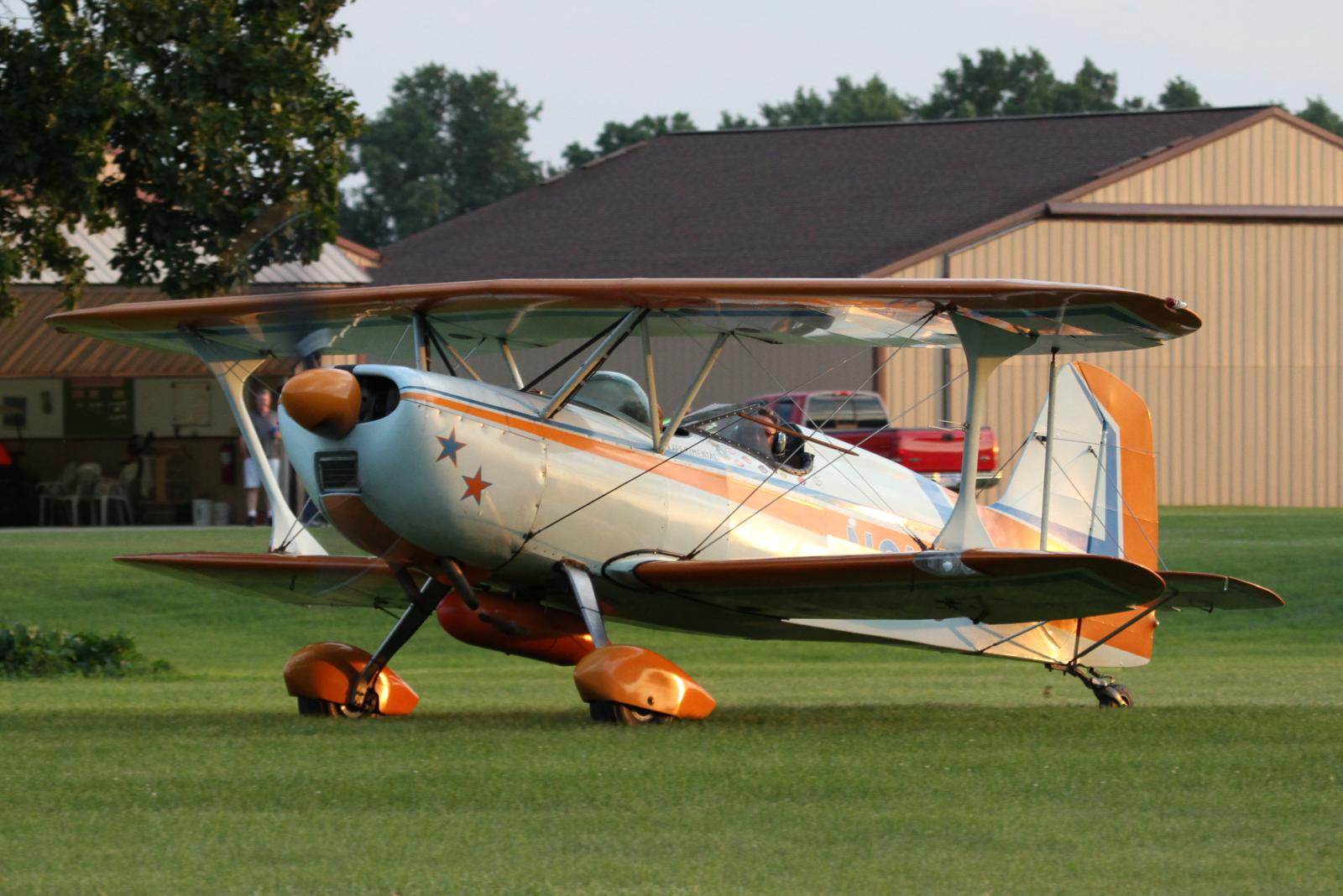 an old fashioned aircraft sits in the grass