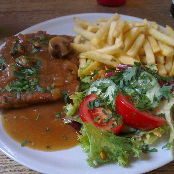 this is a plate with meat, salad and french fries