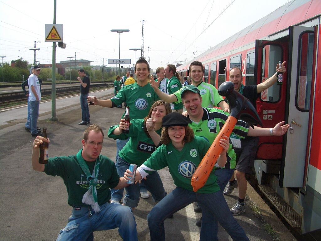 people in green shirts standing next to a train
