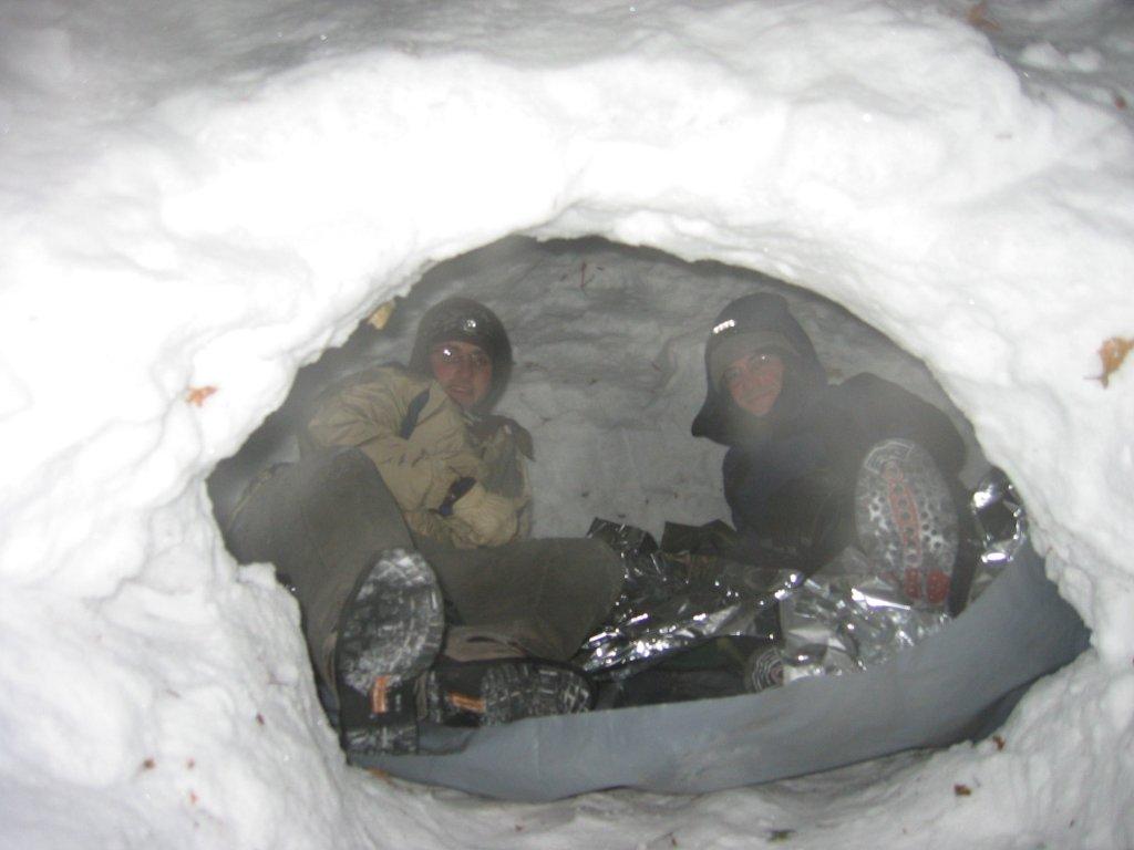 two men sitting inside of an ice cave