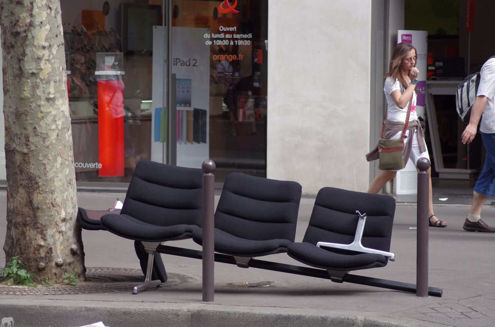 black and white chair sitting on the sidewalk in front of a store