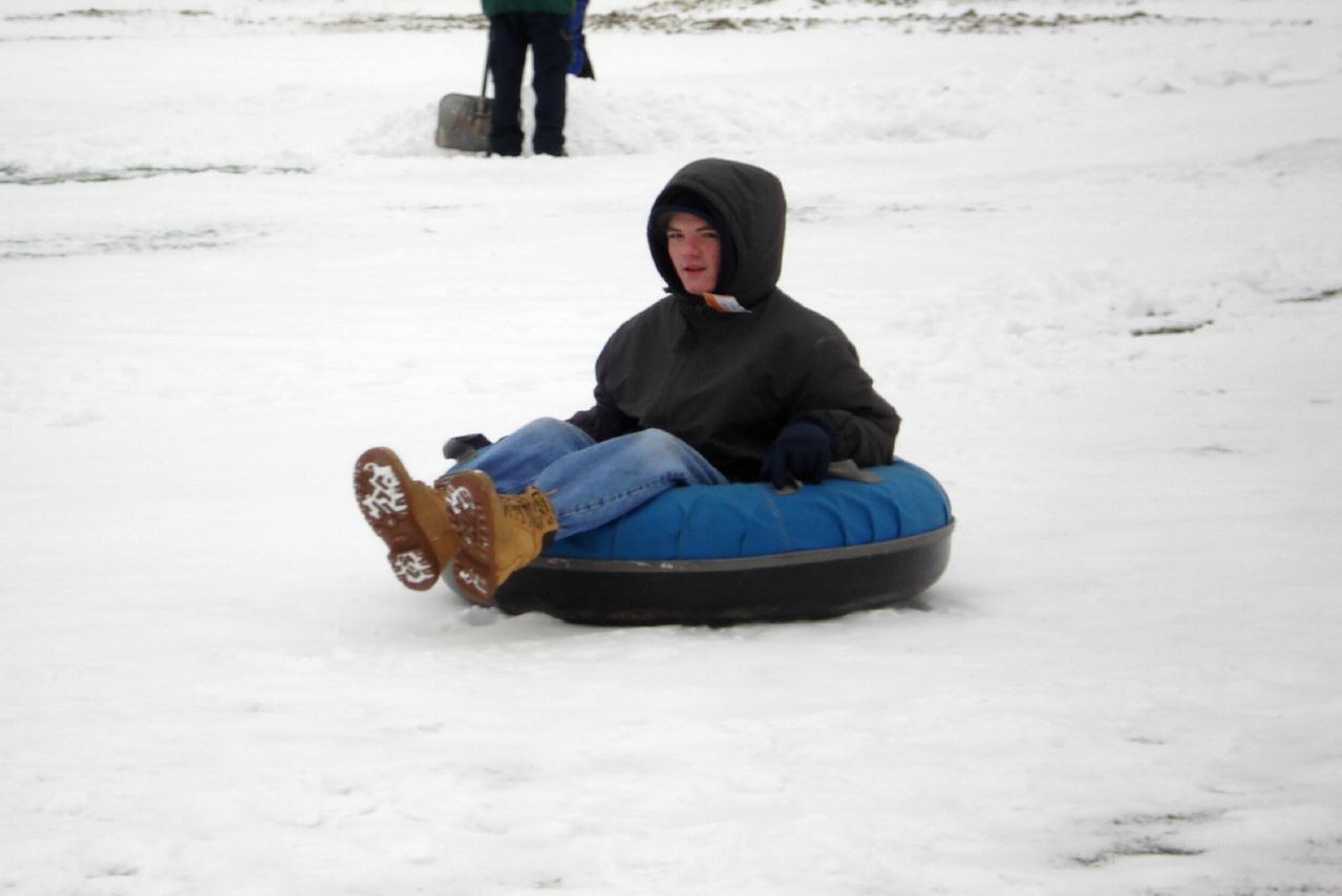 a man riding a tube down the side of a snow covered slope