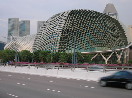 a car driving past a futuristic looking building