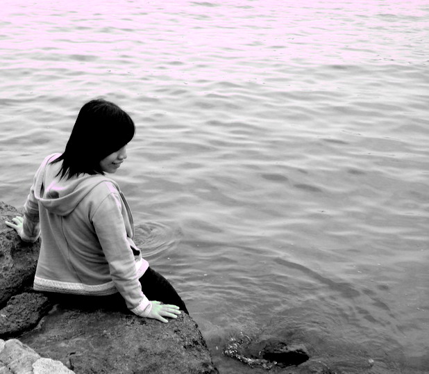 a woman sitting on the rocks near the water