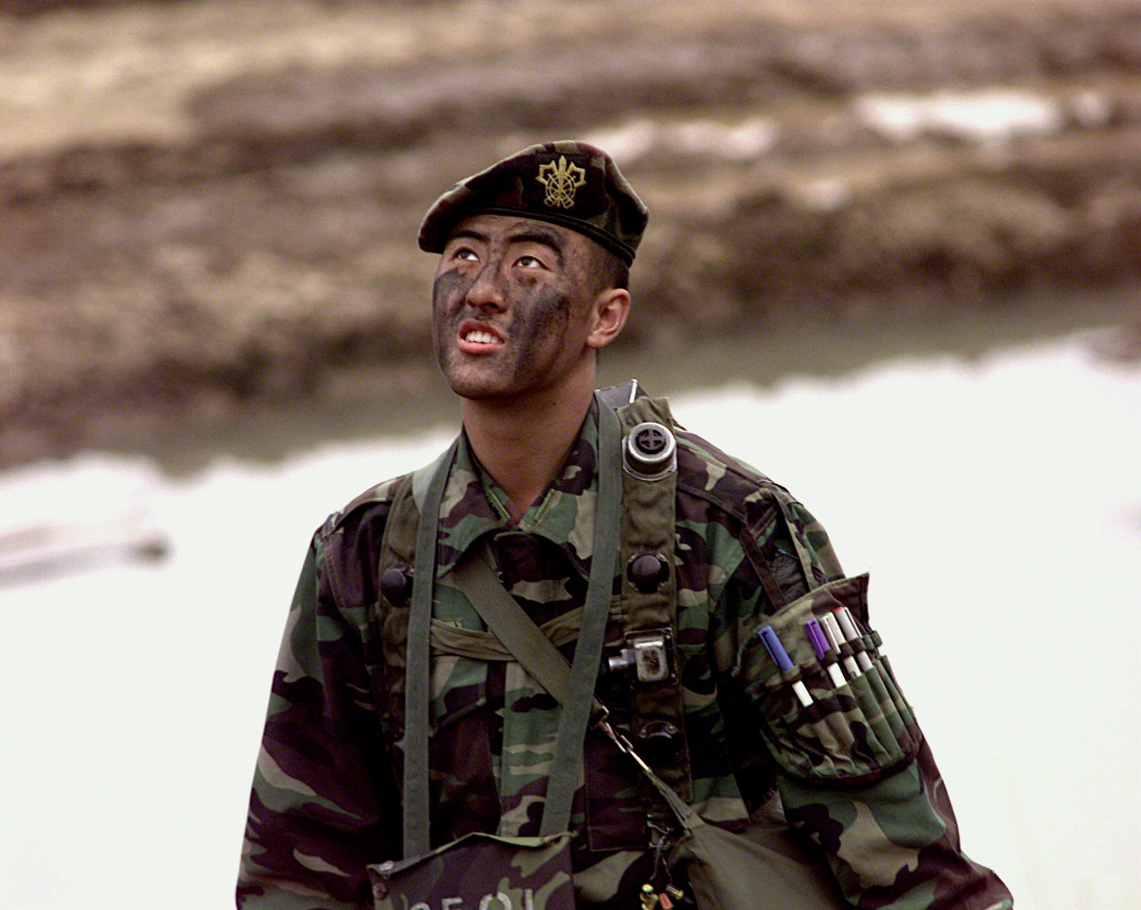 a soldier in camouflage has painted his face and hands