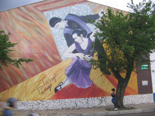 a large mural painted on a building behind a tree