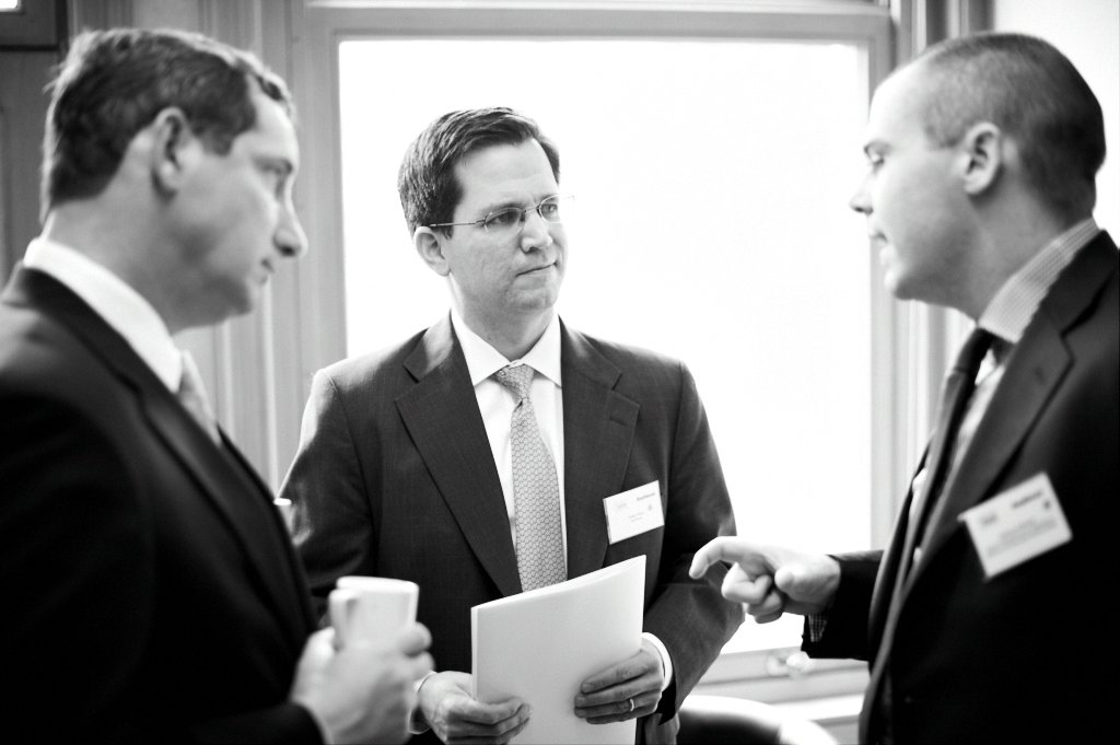 three men wearing suits talking in a room