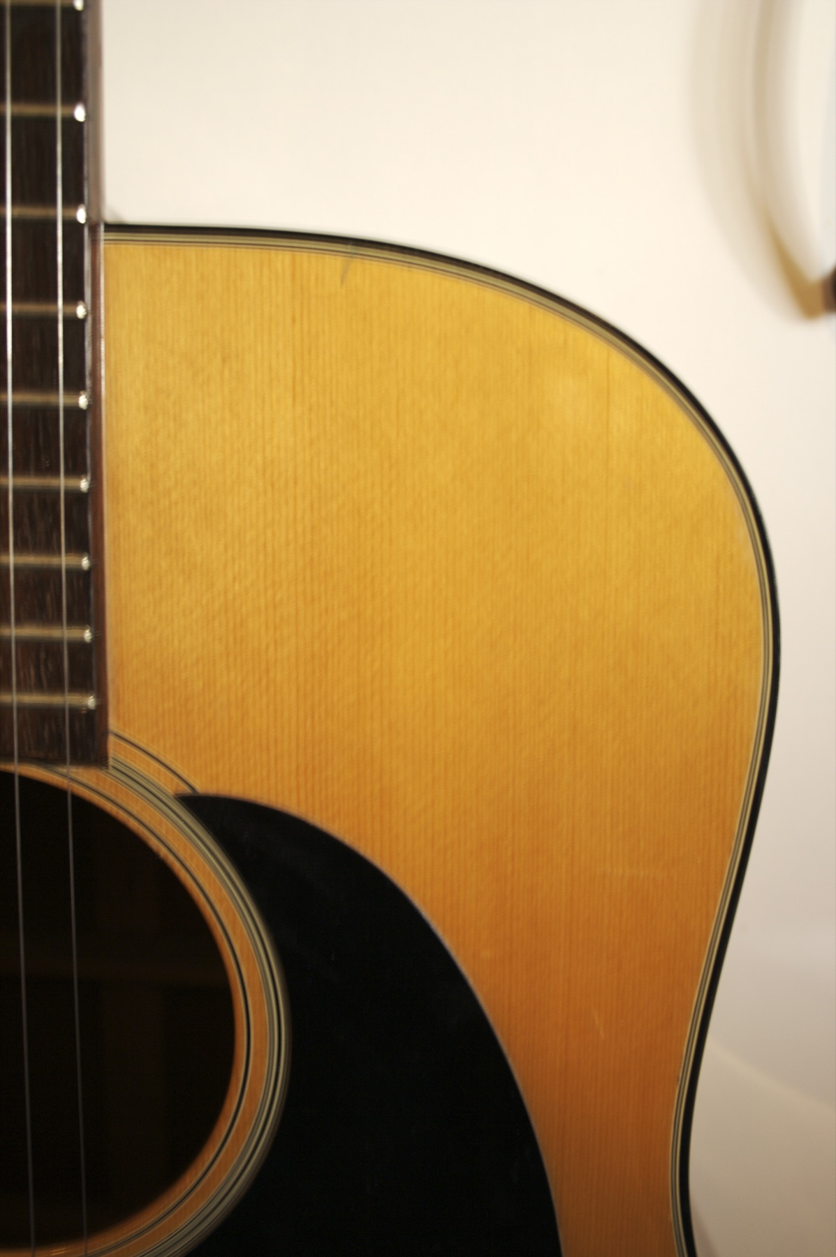 closeup of an acoustic guitar leaning up against the wall