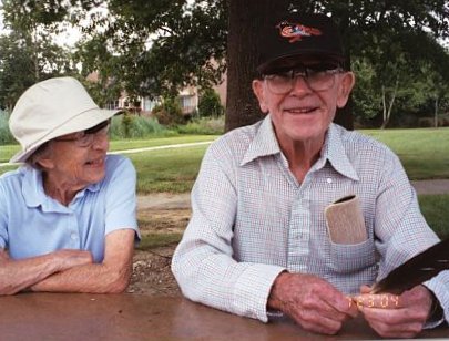 two elderly people sitting by a tree in the park