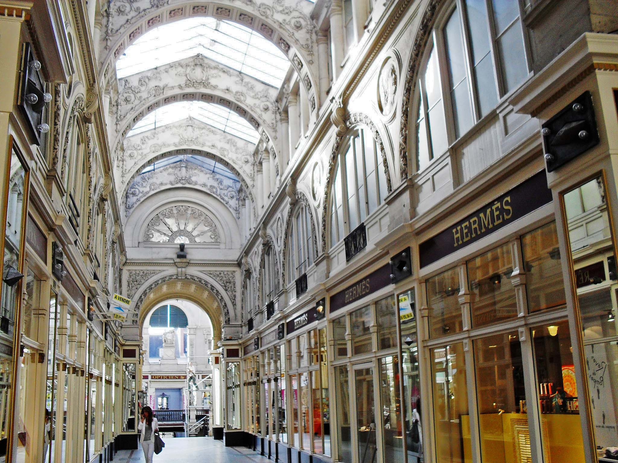 a large, long hallway inside of a building with a glass ceiling and stone arches on one wall and stonework along the other