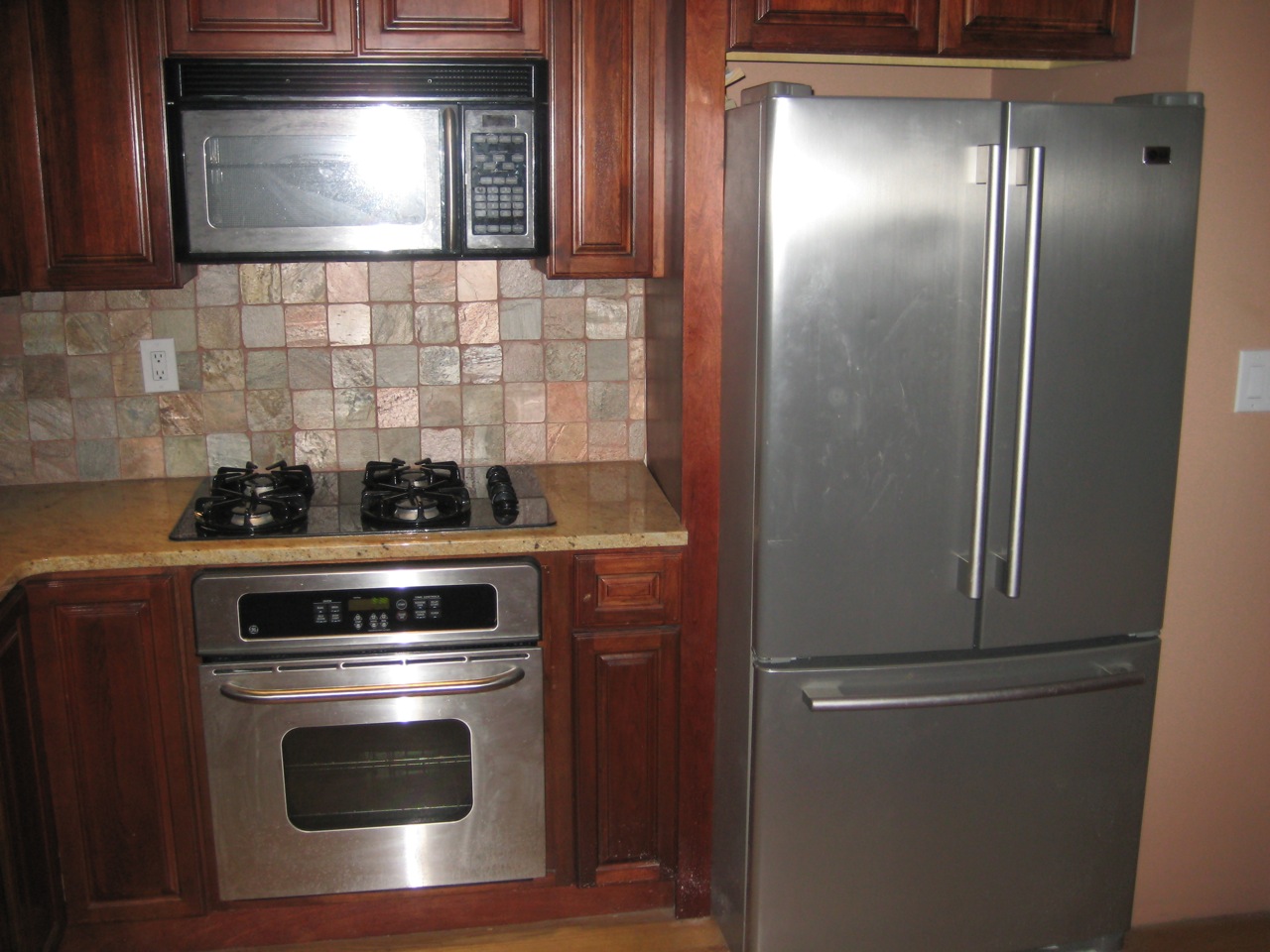 a kitchen has stainless steel appliances, wood cabinets, and tile backsplash