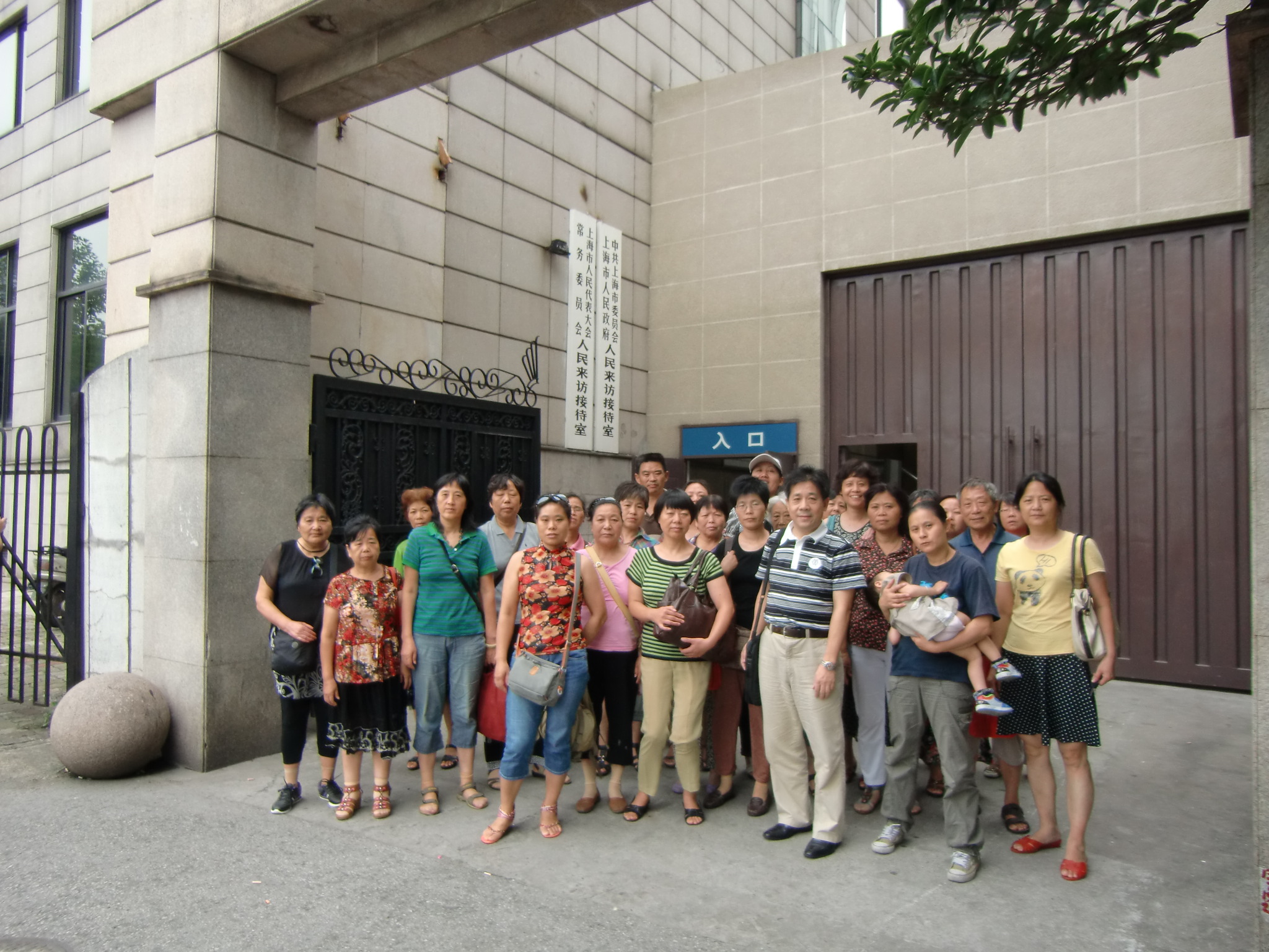 a group of people standing outside of a building next to a wall