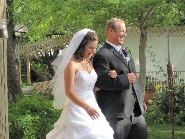 a man in a gray suit and a woman in a white dress walk toward each other