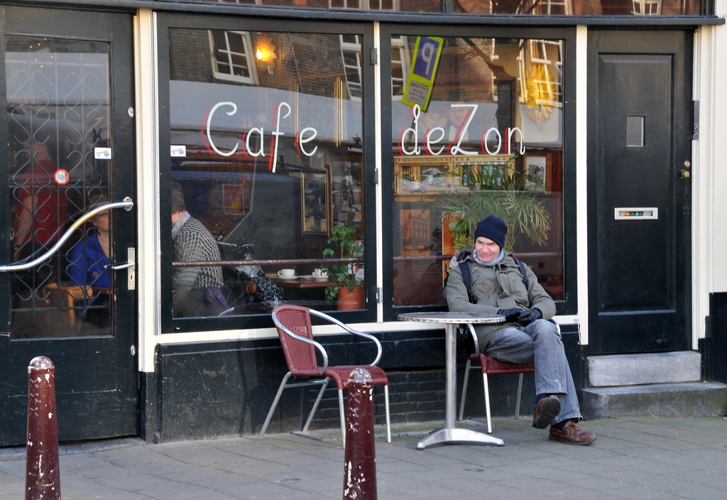 a person sitting on a bench in front of a cafe