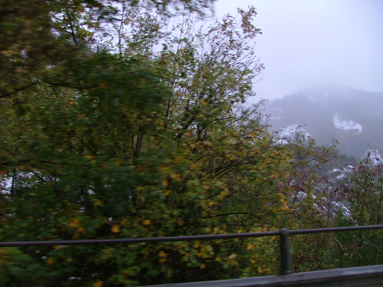 a hillside and mountains are seen through a foggy window