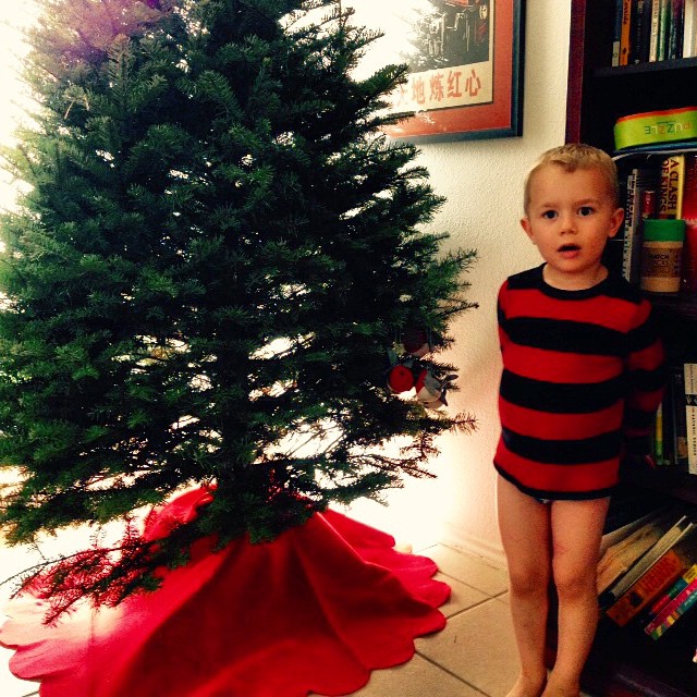 a small child standing in front of a christmas tree