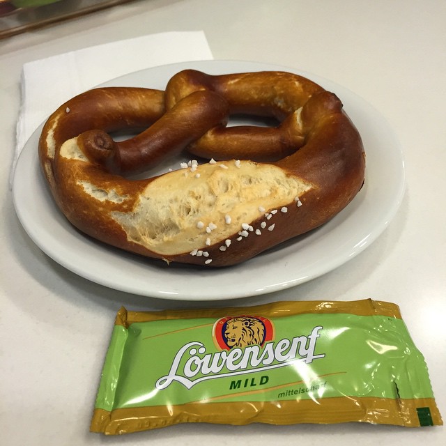 two large pretzels are on a plate next to a bag of peanuts