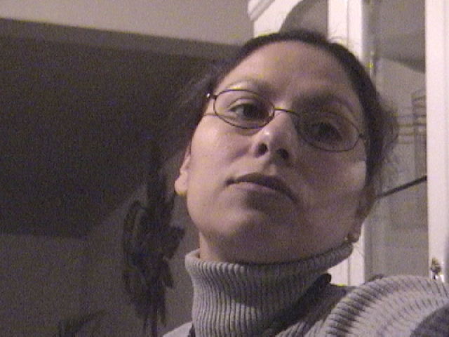 a woman wearing glasses in an unmade room