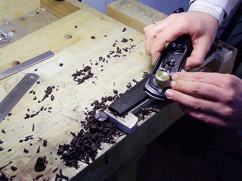 man sharpes his razor blade at the top of a wooden board