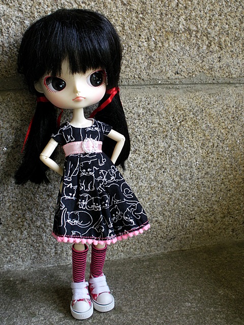 the doll is wearing all black with pink trims