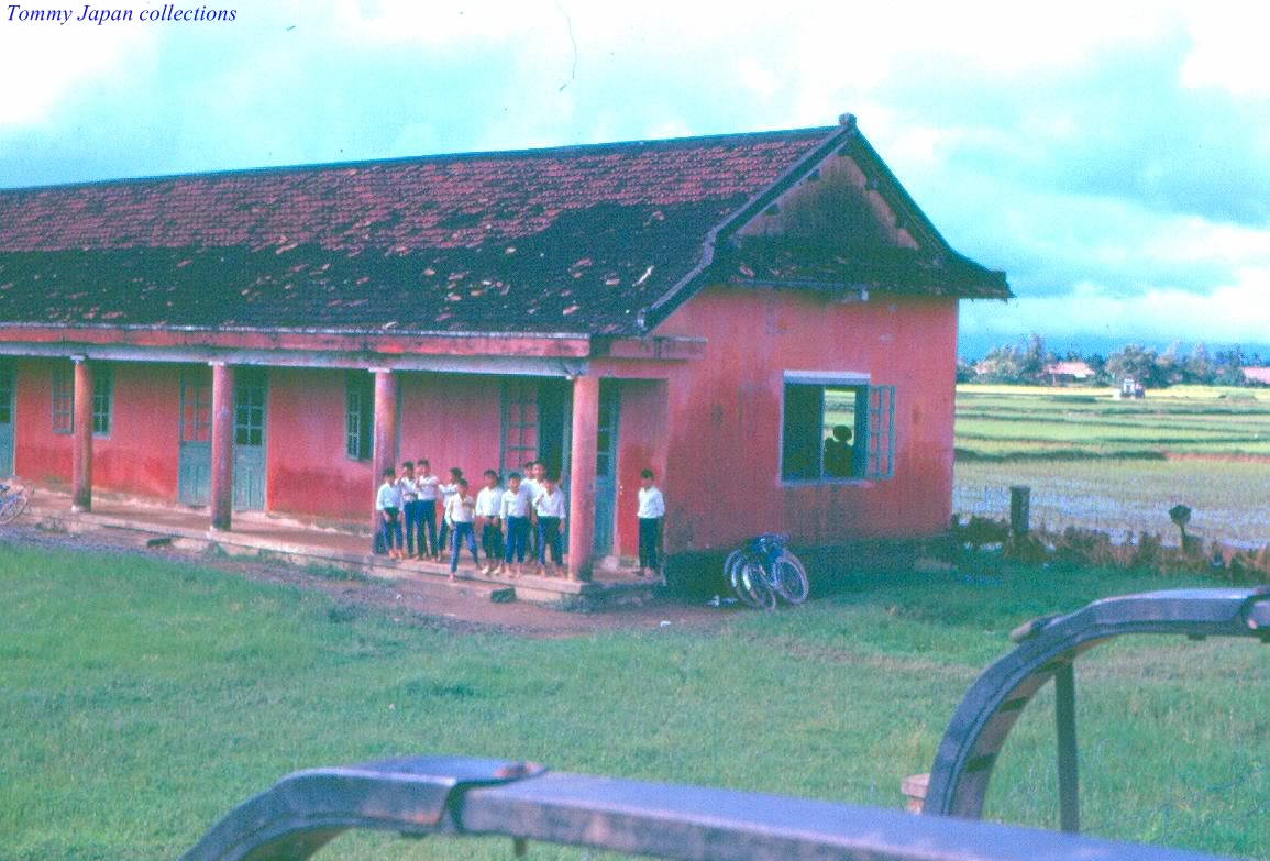 people stand outside of an old red building