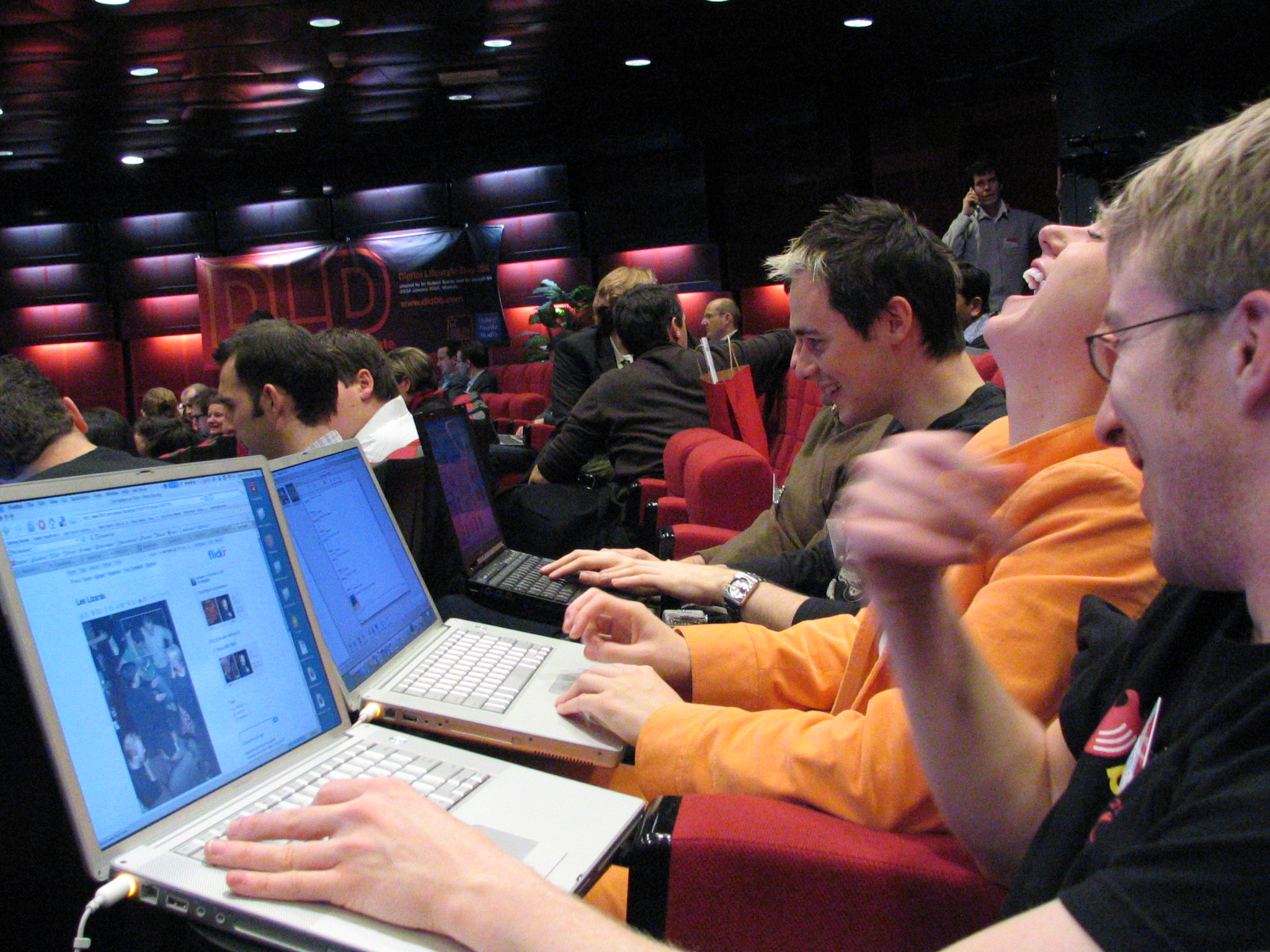 a man in an orange shirt using his lap top