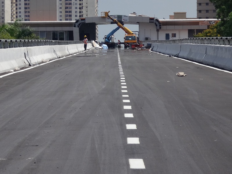 construction workers and trucks are on the side of an empty roadway