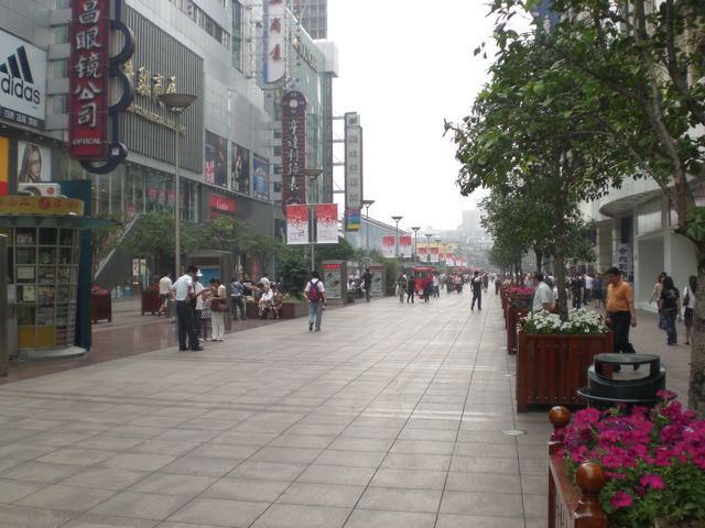 a busy shopping street with people walking and sitting