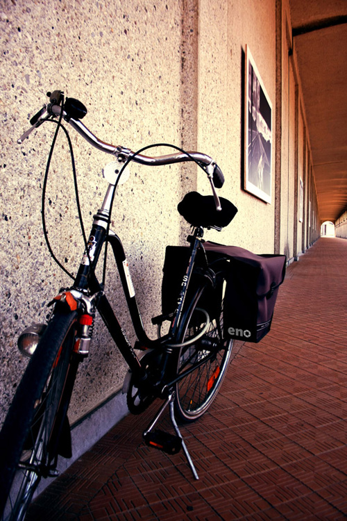 a bike sitting on the side of a building next to a sidewalk