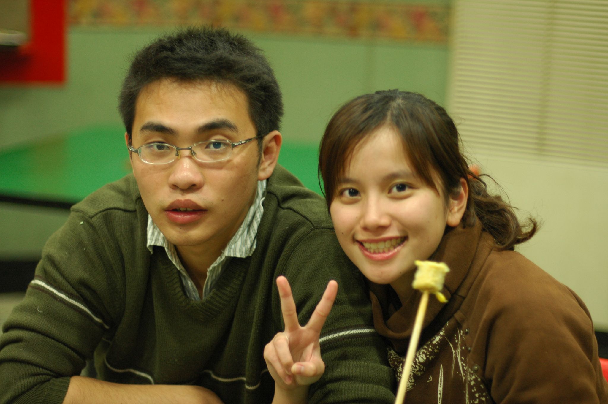 a man and woman pose with a piece of food in their hand