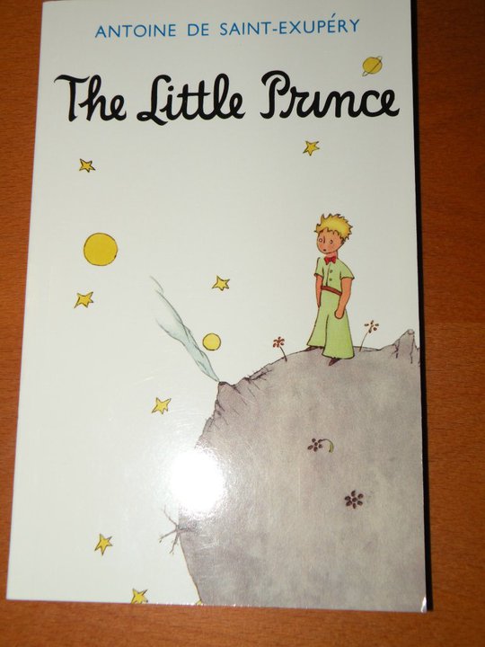 a book about the little prince that is sitting on a wooden surface