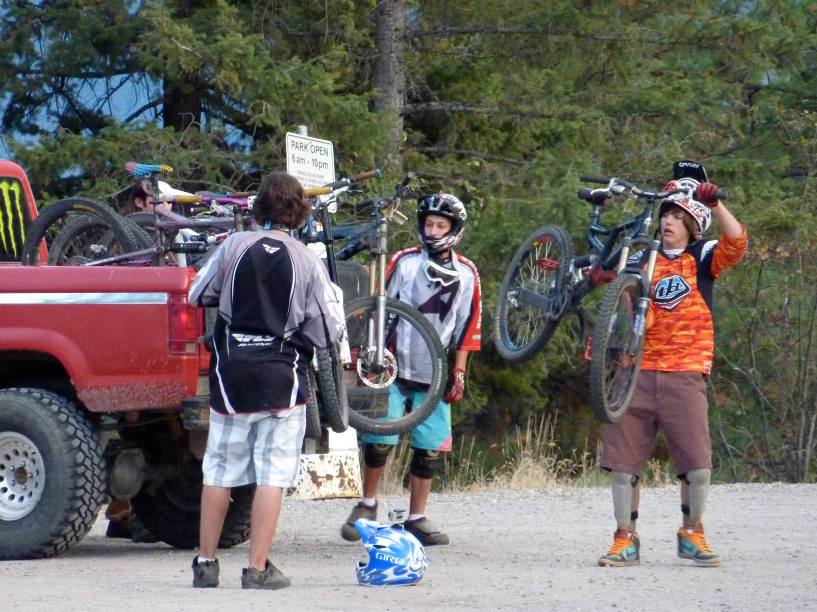 a group of boys holding bikes on their shoulders and standing in front of a red pick up truck