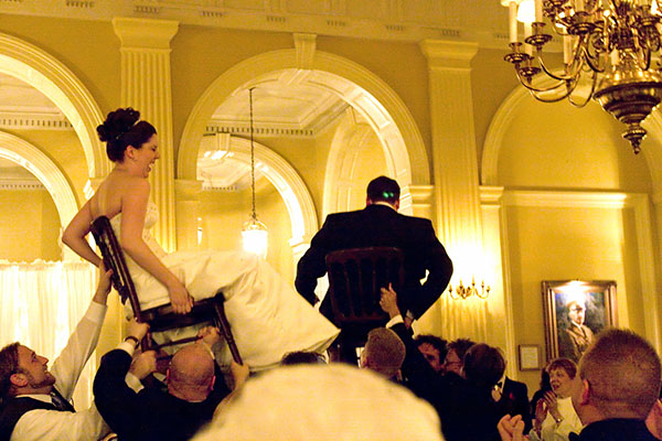 a bride and groom walking on a chair at a wedding