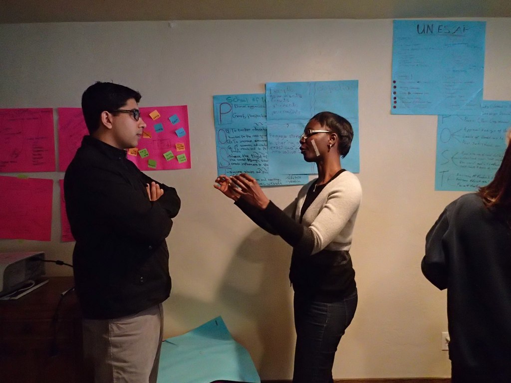 three people standing and talking next to a wall