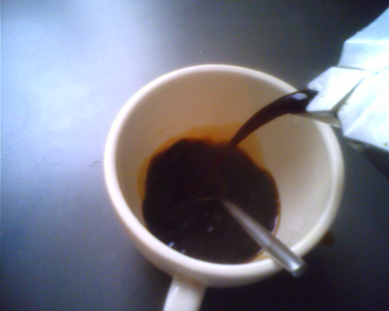 a spoon sitting in a coffee cup filled with brown liquid
