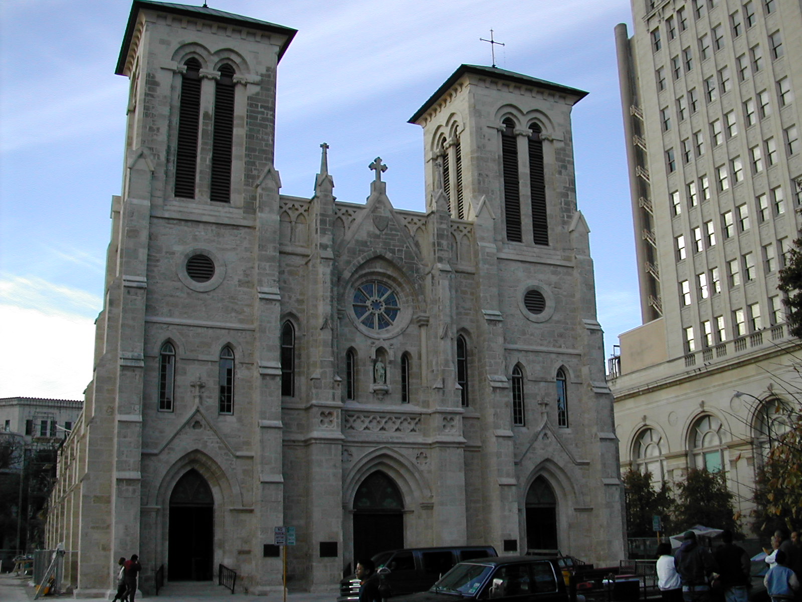 a grey cathedral with towers on a city street
